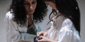 A mother and daughter interact with a smartwatch, showcasing family bonding with modern tech.