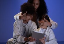 A mother covering her children's eyes while they hold a tablet, illustrating parental control.