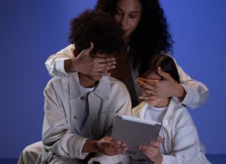 Миллер проведёт круглый стол по закону о безопасности соцсетей A mother covering her children's eyes while they hold a tablet, illustrating parental control.