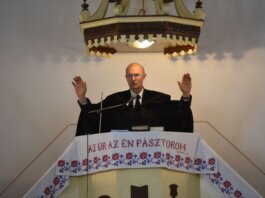 A pastor delivers a sermon inside a church in Vásárosnamény, offering blessings from the pulpit.