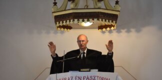 A pastor delivers a sermon inside a church in Vásárosnamény, offering blessings from the pulpit.