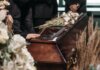 24-летняя женщина погибла в ДТП на шоссе в Гамильтоне A poignant funeral moment with mourners gathered around a coffin decorated with flowers.