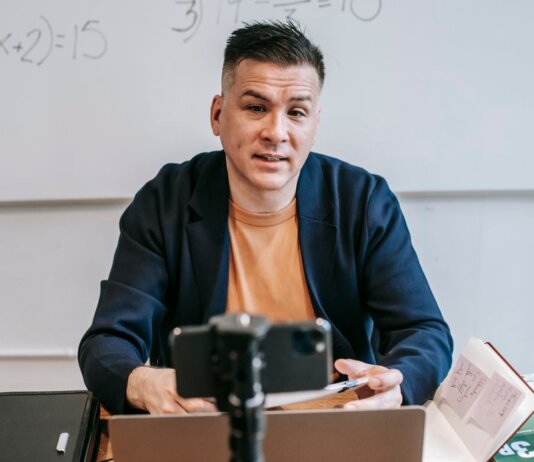 A professional educator conducting an online class, engaging with students via video call.