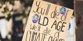 A protest sign highlighting climate change issues during a daylight rally.