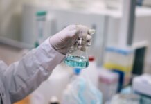 A scientist in a laboratory analyzing a fluid in an Erlenmeyer flask.