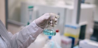 A scientist in a laboratory analyzing a fluid in an Erlenmeyer flask.