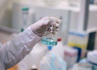 A scientist in a laboratory analyzing a fluid in an Erlenmeyer flask.