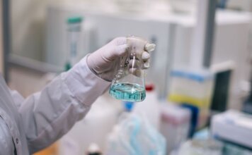 A scientist in a laboratory analyzing a fluid in an Erlenmeyer flask.