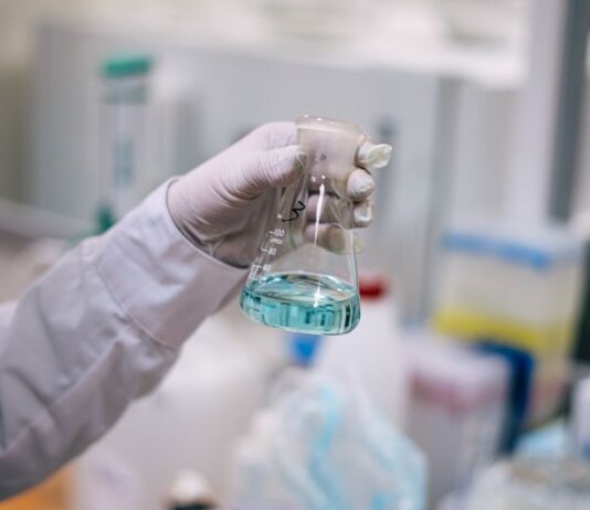 A scientist in a laboratory analyzing a fluid in an Erlenmeyer flask.