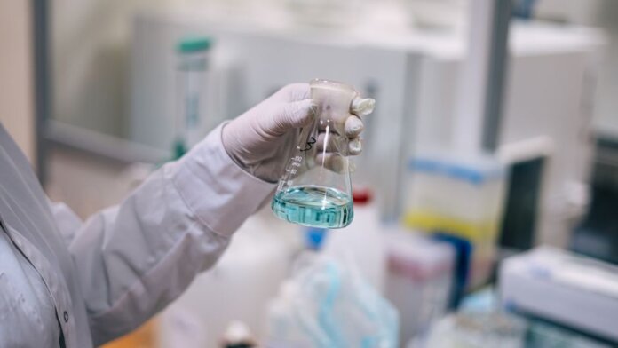 A scientist in a laboratory analyzing a fluid in an Erlenmeyer flask. A scientist in a laboratory analyzing a fluid in an Erlenmeyer flask.