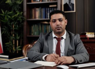 Канада назначила нового посла в Королевстве Бахрейн A serious businessman in a suit writing at his desk in a formal office setting.