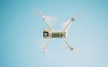 Напоминание: запуск дронов вблизи лесных пожаров незаконен и опасен A sleek white drone flying under a clear blue sky, capturing aerial views.