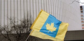 A unique flag blending Ukrainian colors with a Canadian maple leaf in an outdoor setting.