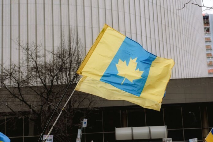 A unique flag blending Ukrainian colors with a Canadian maple leaf in an outdoor setting.