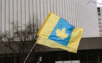 Канада станет со-рамочной нацией многонациональной дивизии НАТО в Латвии A unique flag blending Ukrainian colors with a Canadian maple leaf in an outdoor setting.