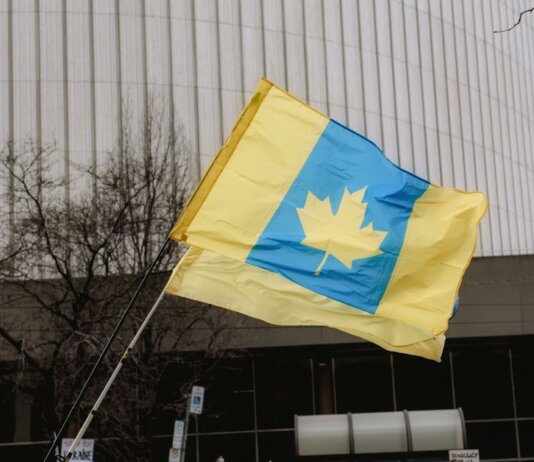 A unique flag blending Ukrainian colors with a Canadian maple leaf in an outdoor setting.