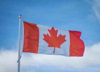 A vibrant Canadian flag waving in the breeze against a bright blue sky, symbolizing national pride.