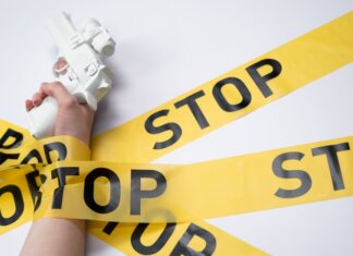Консерваторы: насильственные преступления в Канаде продолжают расти A white toy gun held by a hand wrapped in yellow stop tape on a white background, conveying a message of caution.