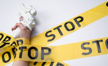 Консерваторы: насильственные преступления в Канаде продолжают расти A white toy gun held by a hand wrapped in yellow stop tape on a white background, conveying a message of caution.
