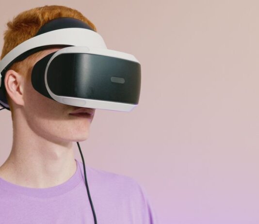 A young caucasian man wearing VR glasses, experiencing virtual reality.