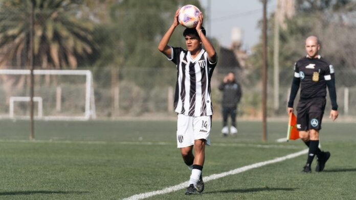 A young soccer player prepares to throw-in during a match on a sunny day, with referee nearby. A young soccer player prepares to throw-in during a match on a sunny day, with referee nearby.