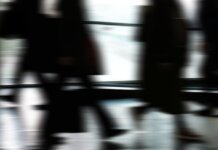 Abstract blurred motion of people walking indoors, depicting urban life and busy routines.