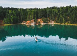 Aerial shot of a woman paddle boarding on a serene lake in Rezh, Russia, surrounded by lush greenery.