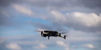 Aerial view of a drone flying over snow-covered mountains with dramatic clouds.