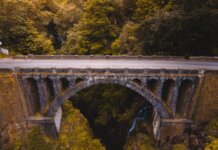 Aerial view of a historic stone bridge in Madeira, surrounded by lush greenery and dramatic landscapes.