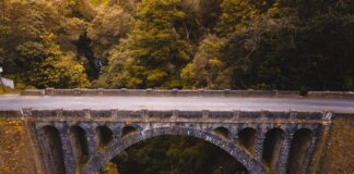 Aerial view of a historic stone bridge in Madeira, surrounded by lush greenery and dramatic landscapes.