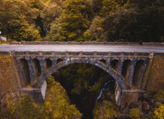 Aerial view of a historic stone bridge in Madeira, surrounded by lush greenery and dramatic landscapes.