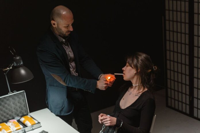An intense scene depicting a suspect lighting a cigarette during an interrogation.