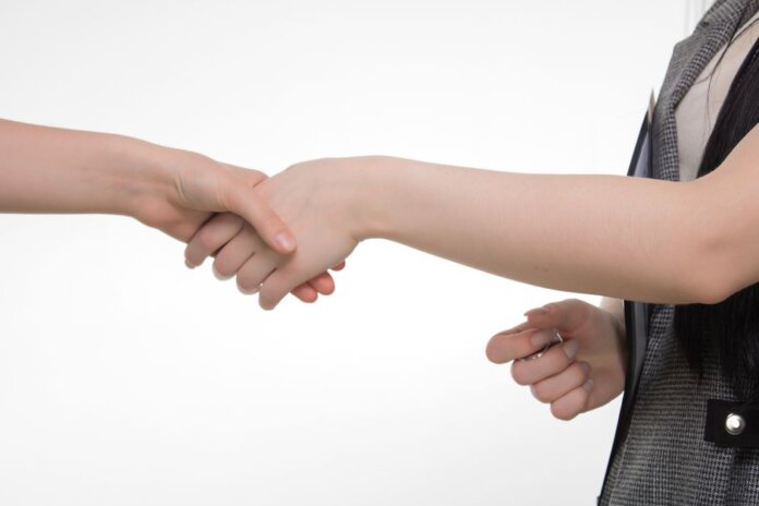 An up-close image of two people shaking hands in a professional setting against a white background. An up-close image of two people shaking hands in a professional setting against a white background.