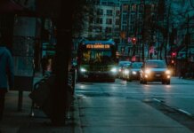 City street at night featuring a bus heading to Burrard Station with urban buildings in the background.