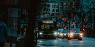 City street at night featuring a bus heading to Burrard Station with urban buildings in the background.