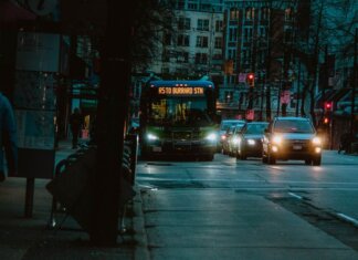 Как TransLink борется с задержками автобусов City street at night featuring a bus heading to Burrard Station with urban buildings in the background.