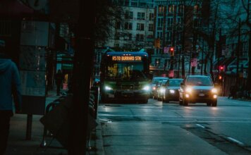 Как TransLink борется с задержками автобусов City street at night featuring a bus heading to Burrard Station with urban buildings in the background.