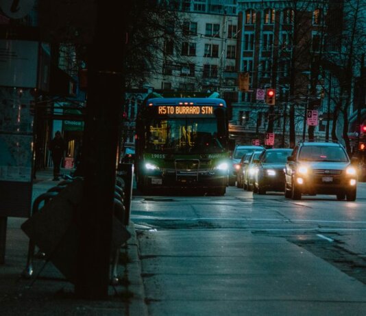 City street at night featuring a bus heading to Burrard Station with urban buildings in the background.