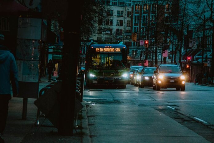 City street at night featuring a bus heading to Burrard Station with urban buildings in the background. City street at night featuring a bus heading to Burrard Station with urban buildings in the background.