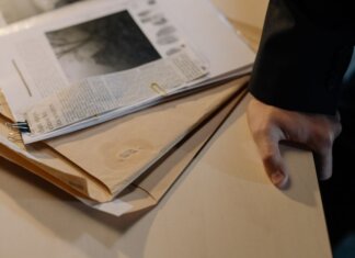 В Британской Колумбии изъяли 22 нелегальных огнестрельных оружия Close-up of a hand resting on a desk near a stack of investigative documents and newspaper clippings.