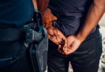 Close-up of a police officer arresting a suspect with visible firearm outdoors.