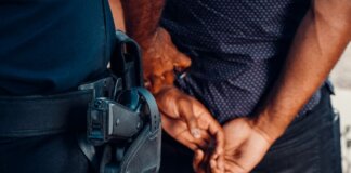 Close-up of a police officer arresting a suspect with visible firearm outdoors.