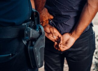 Close-up of a police officer arresting a suspect with visible firearm outdoors.