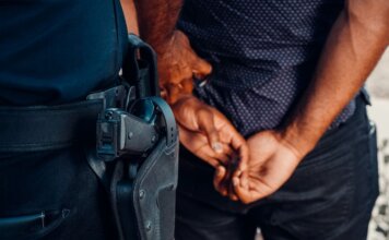 Close-up of a police officer arresting a suspect with visible firearm outdoors.