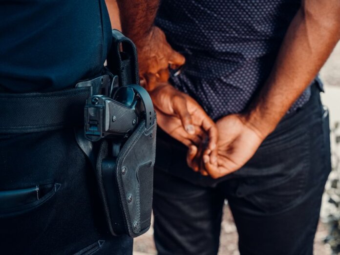 Close-up of a police officer arresting a suspect with visible firearm outdoors. Close-up of a police officer arresting a suspect with visible firearm outdoors.