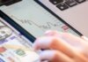 Close-up of a smartphone displaying stock market data over a dollar bill on a desk.