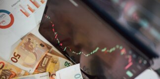Close-up of euro banknotes with a digital stock market chart displaying a downward trend, symbolizing financial volatility.
