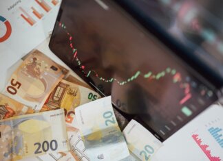 Close-up of euro banknotes with a digital stock market chart displaying a downward trend, symbolizing financial volatility.