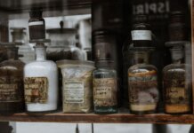 Collection of vintage apothecary bottles with handwritten labels on a wooden shelf, reflecting a medieval charm.