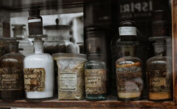 Collection of vintage apothecary bottles with handwritten labels on a wooden shelf, reflecting a medieval charm.